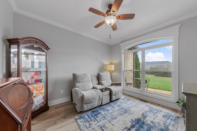 living area with ceiling fan, light hardwood / wood-style floors, and crown molding