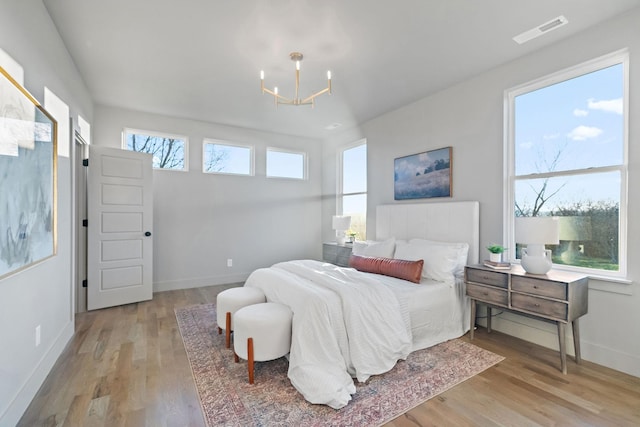 bedroom with an inviting chandelier and light wood-type flooring