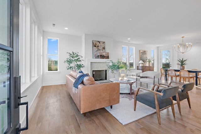 living room featuring an inviting chandelier, light wood-type flooring, and a wealth of natural light