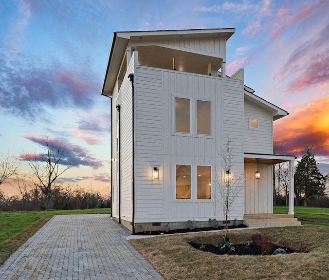 back house at dusk with a lawn