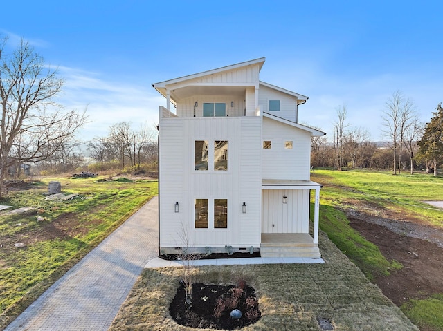 rear view of house featuring a lawn and a balcony