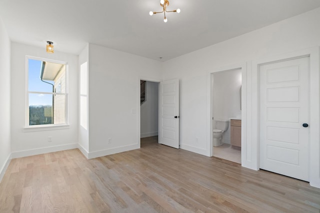 unfurnished bedroom with light hardwood / wood-style floors and connected bathroom