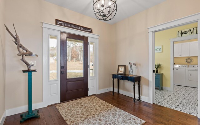 entryway with a healthy amount of sunlight, separate washer and dryer, dark wood-type flooring, and a notable chandelier