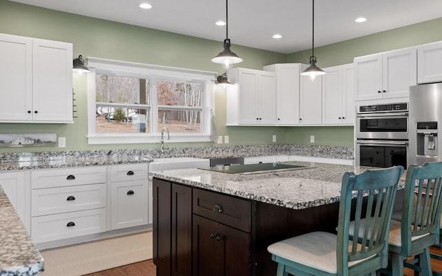 kitchen with a kitchen breakfast bar, hanging light fixtures, white cabinets, and stainless steel double oven