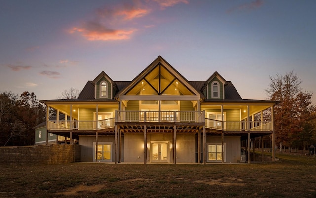 back house at dusk featuring a deck and french doors