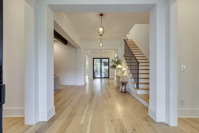 foyer featuring french doors, light wood-type flooring, and ornamental molding