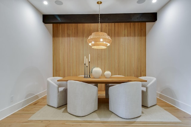 dining area featuring beamed ceiling, hardwood / wood-style flooring, and a chandelier