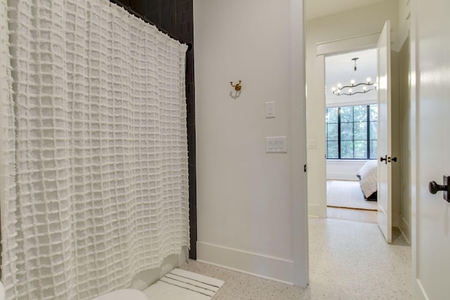 bathroom with a shower with shower curtain and a notable chandelier