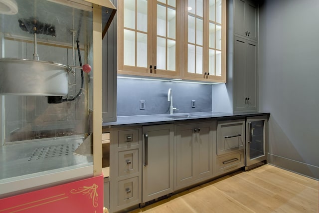 bar featuring wine cooler, sink, gray cabinets, and light hardwood / wood-style flooring