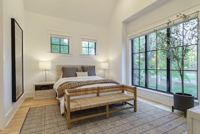 bedroom featuring lofted ceiling, light wood-type flooring, and multiple windows