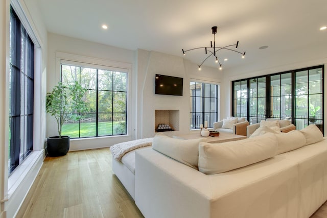 living room with a fireplace, light wood-type flooring, and a notable chandelier