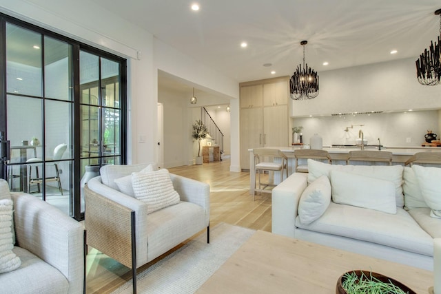 living room featuring light wood-type flooring, sink, and an inviting chandelier