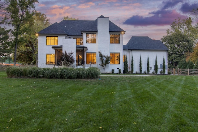 back house at dusk with a lawn