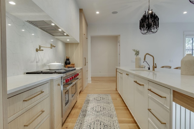 kitchen with light stone counters, sink, double oven range, and light hardwood / wood-style flooring