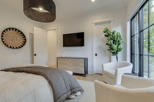 bedroom with multiple windows, crown molding, and light hardwood / wood-style floors