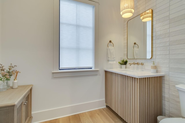 bathroom featuring wood-type flooring, vanity, and tile walls