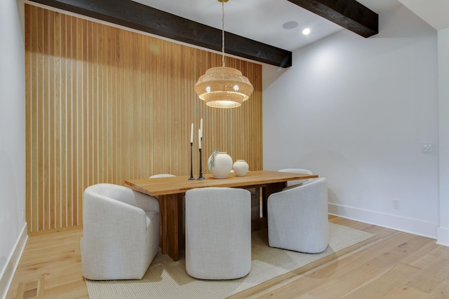 dining area with wood walls, beamed ceiling, and hardwood / wood-style flooring