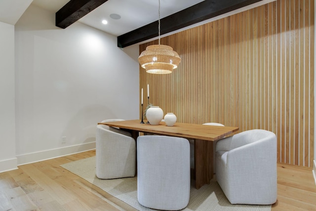 dining area featuring beamed ceiling, wood walls, and wood-type flooring