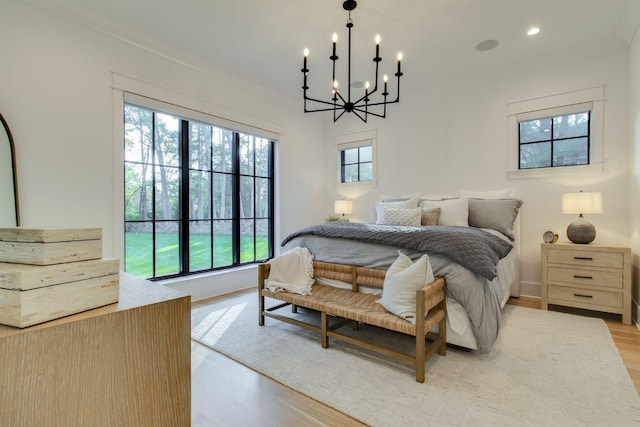 bedroom with an inviting chandelier, crown molding, and light hardwood / wood-style flooring