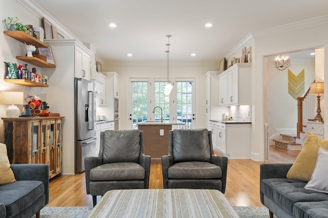 living room with a chandelier, light hardwood / wood-style floors, and ornamental molding