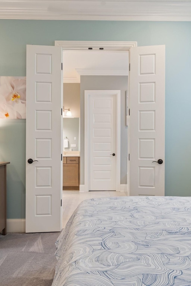 carpeted bedroom featuring ensuite bath and crown molding