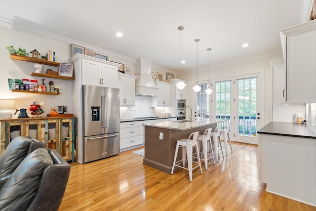 kitchen with white cabinets, pendant lighting, premium range hood, and stainless steel appliances