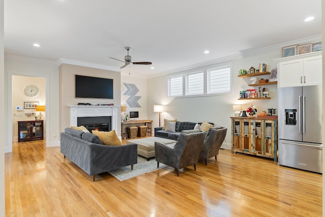 living room with light wood-type flooring, ceiling fan, and crown molding