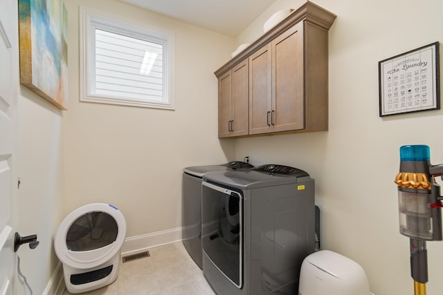 laundry room featuring washer and dryer, cabinets, and light tile patterned flooring