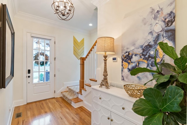 foyer entrance with a notable chandelier, crown molding, and light hardwood / wood-style flooring