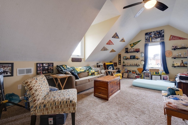 living room with carpet flooring, ceiling fan, lofted ceiling, and a textured ceiling