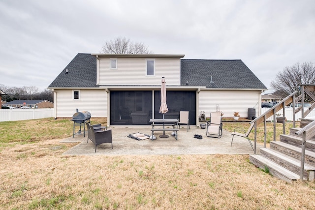 rear view of property featuring a lawn, a sunroom, and a patio