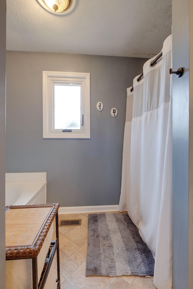 bathroom with tile patterned flooring and a textured ceiling