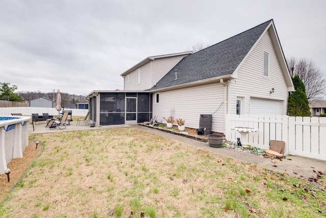 back of property with a sunroom, a patio, a fenced in pool, a garage, and a lawn