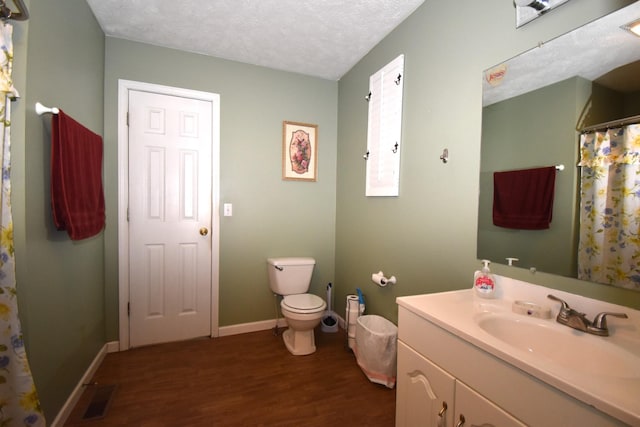 bathroom featuring wood-type flooring, toilet, a textured ceiling, and vanity