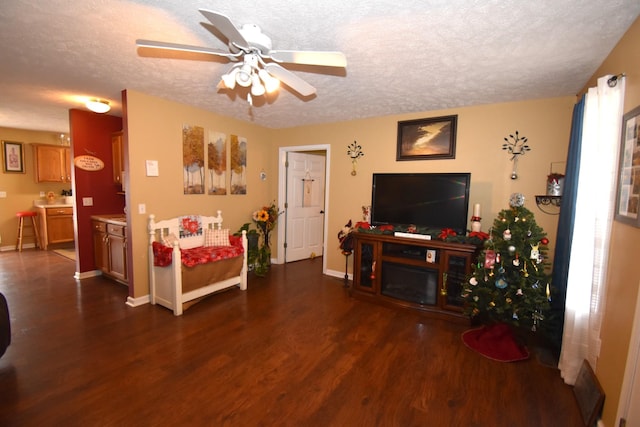 living room with ceiling fan, dark hardwood / wood-style floors, and a textured ceiling