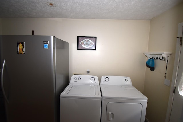 laundry room with washing machine and clothes dryer and a textured ceiling