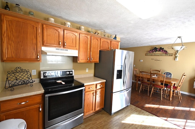 kitchen featuring decorative light fixtures, dark wood-type flooring, a textured ceiling, and appliances with stainless steel finishes