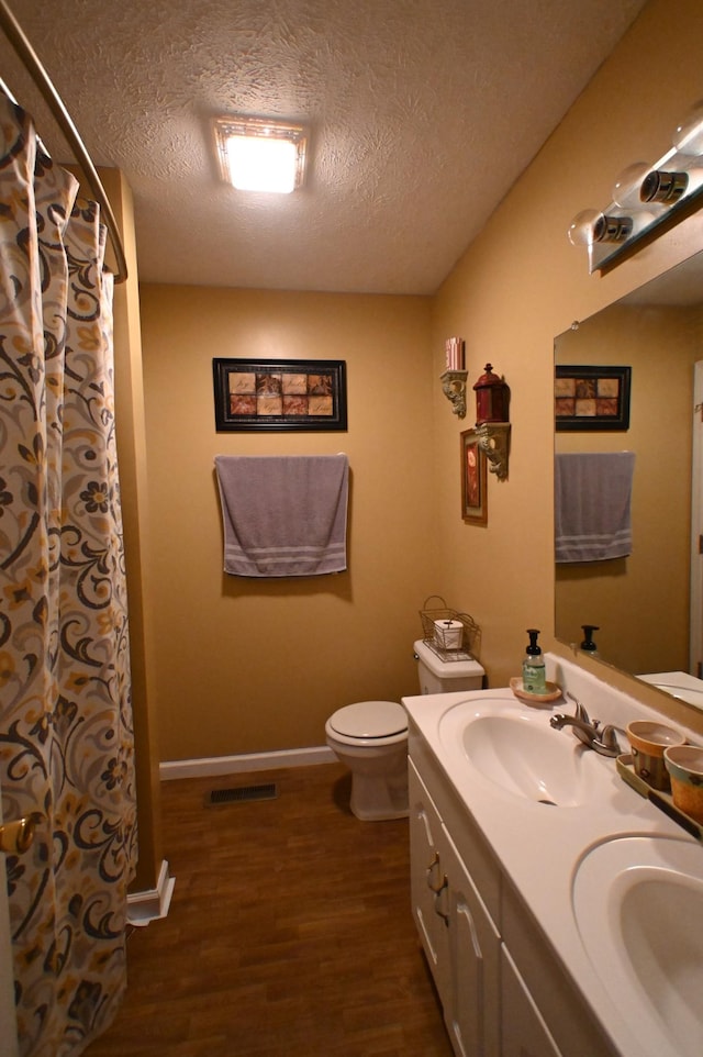 bathroom featuring vanity, hardwood / wood-style floors, a textured ceiling, and toilet