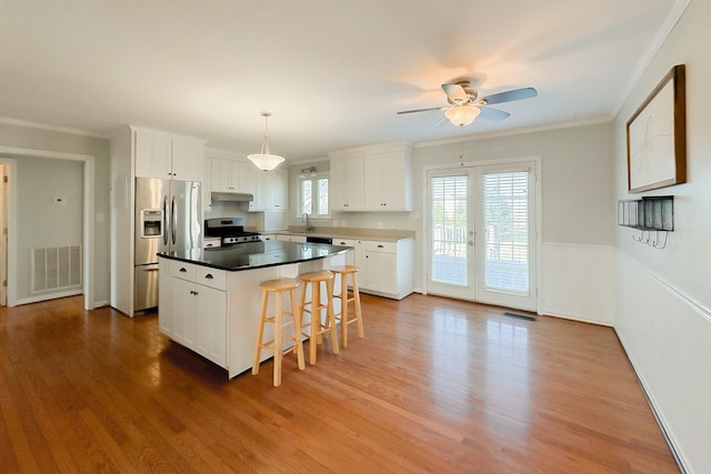 kitchen featuring stainless steel appliances, white cabinetry, a kitchen island, and hanging light fixtures