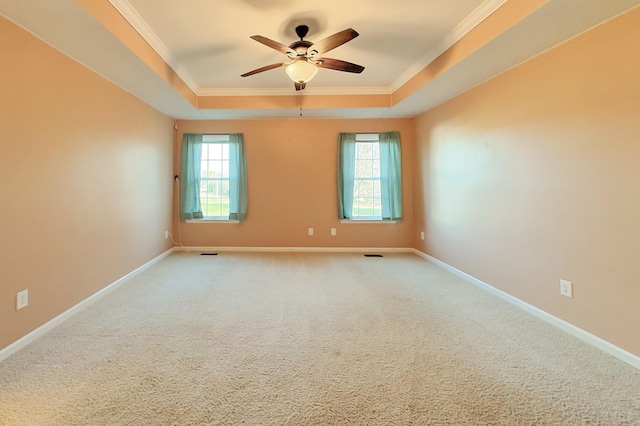 unfurnished room featuring a raised ceiling, crown molding, carpet, and ceiling fan