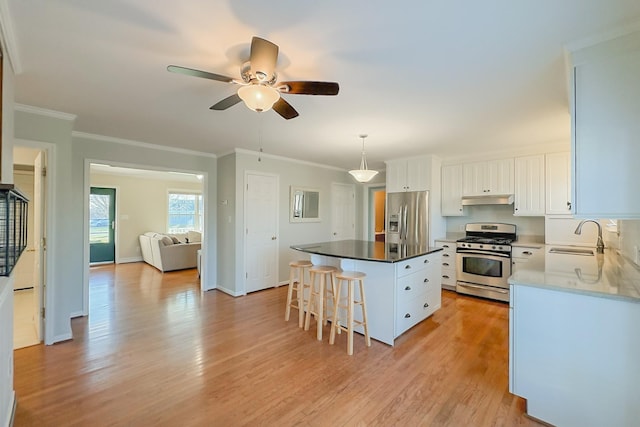 kitchen with appliances with stainless steel finishes, a center island, white cabinets, and decorative light fixtures