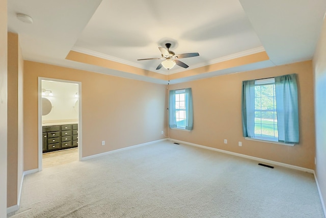 carpeted empty room with crown molding, a tray ceiling, and ceiling fan