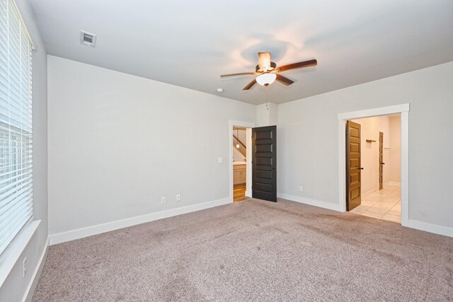 unfurnished bedroom featuring connected bathroom, light colored carpet, and ceiling fan