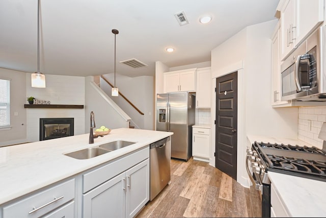 kitchen featuring decorative backsplash, appliances with stainless steel finishes, sink, white cabinets, and hanging light fixtures