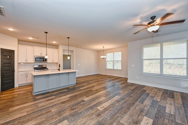 kitchen featuring white cabinets, a center island with sink, hanging light fixtures, appliances with stainless steel finishes, and dark hardwood / wood-style flooring