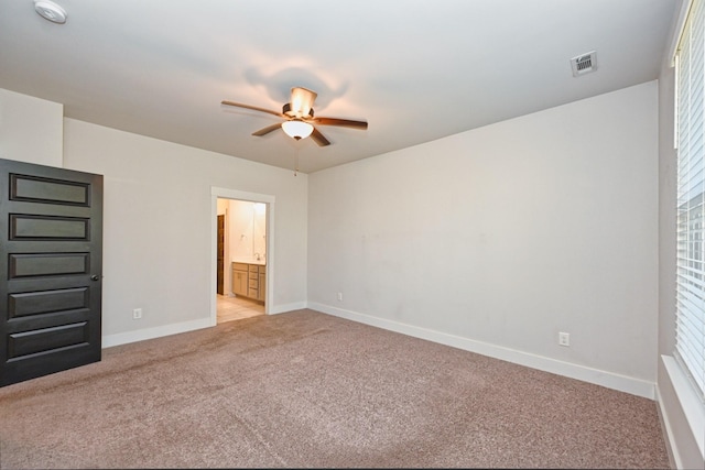 unfurnished bedroom featuring ceiling fan, ensuite bathroom, and light carpet