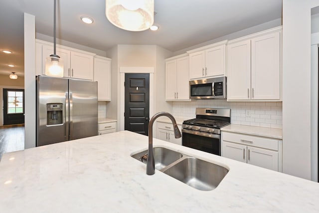 kitchen featuring pendant lighting, sink, white cabinetry, and stainless steel appliances