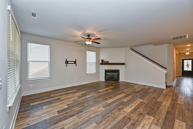 unfurnished living room featuring a fireplace, ceiling fan, and dark wood-type flooring