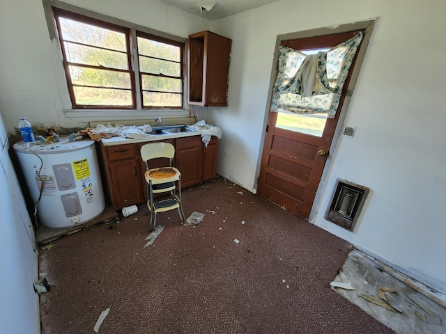 kitchen featuring dark colored carpet, electric water heater, and sink