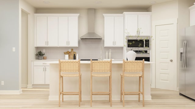 kitchen featuring white cabinets, wall chimney exhaust hood, and stainless steel fridge